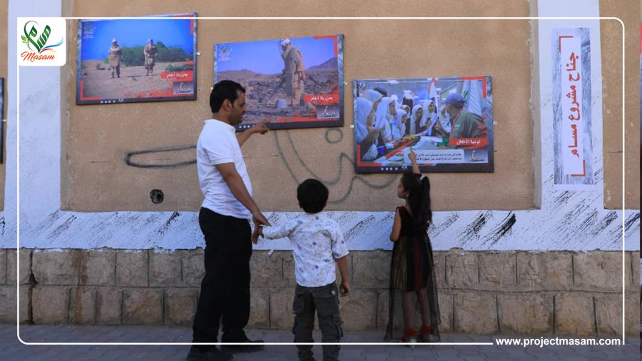 معرض مسام المصور عائلة تنظر إلى صورة من صور معرض مسام بمأرب