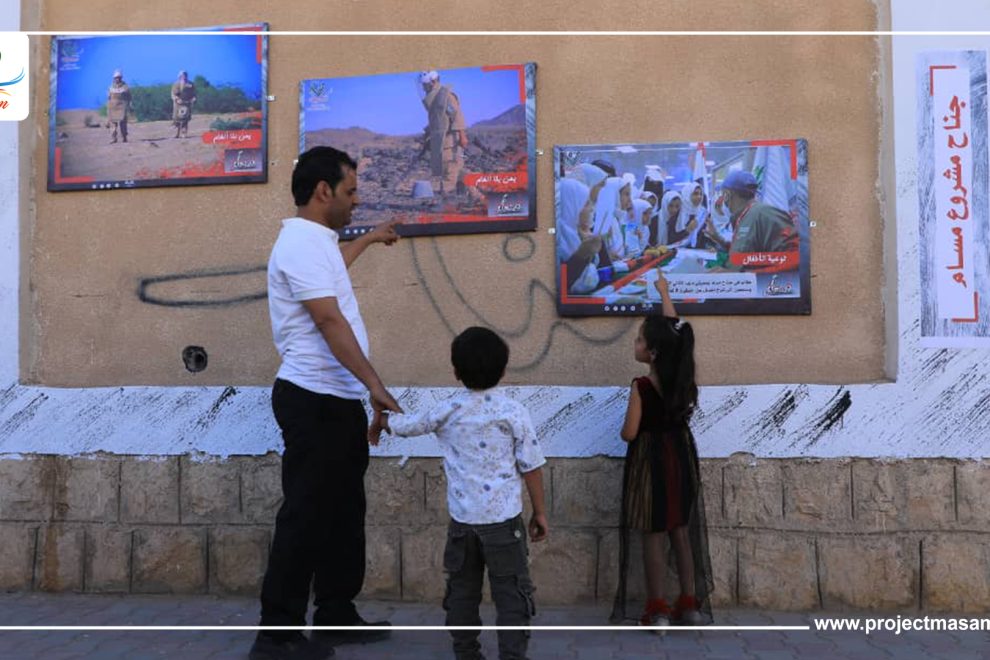 عائلة تنظر إلى صورة من صور معرض مسام بمأرب